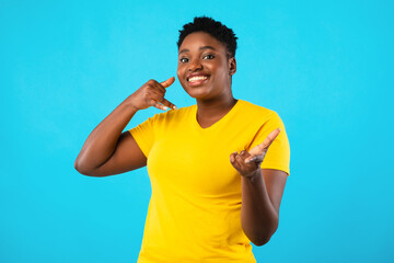 Plus-Size African Woman Gesturing Call Me Over Blue Background