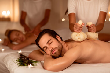 Couple Relaxing During Herbal Back Massage With Aromatic Bags Indoors