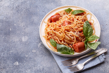 Traditional Italian spaghetti pasta with sausages and basil leaves on concrete background with copy space
