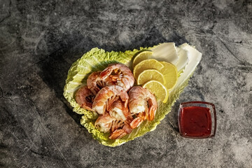 On the leaves of Peking cabbage, king prawns with lingonberry sauce and lemon. The concept of healthy eating
