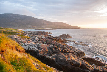 Orange sunset over the Atlantic Ocean seen from the rocky coastline of Barra Island, in the Outer...