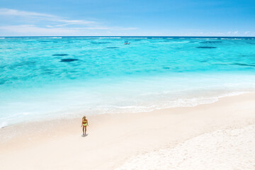Fototapeta na wymiar A little girl stands on Le Morne beach in the Indian Ocean on the island of Mauritius