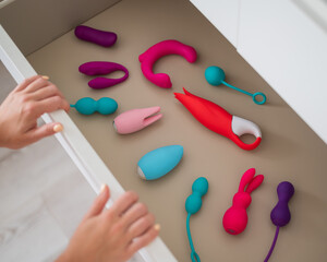 A woman closes the bedside table with a collection of vibrators