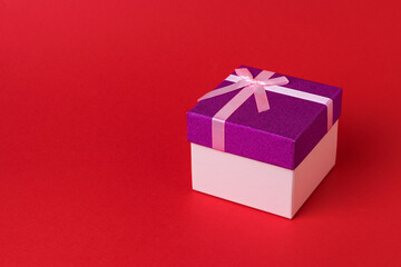 Stylish beautiful gift box with a bow on a red background.