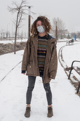 Woman standing in the snow, using protection against corona virus.