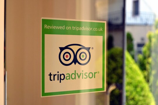 Green sticker with logo and name of the web company "Trip advisor" on the hotel door. Reviews of hotels, restaurants, attractions or other travel related places. Golem / Durres, Albania - June 13 2019