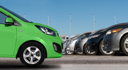 Fototapeta na wymiar Green car on a background of cars in a rows. 