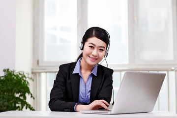 Business woman with a headset using computer