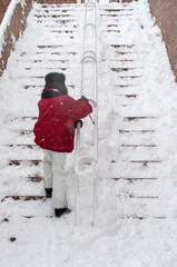 Young woman trying to go upstairs after a strong snowy storm. 