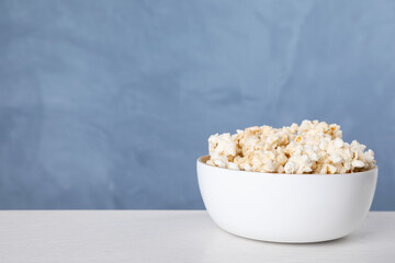 Delicious popcorn on white wooden table. Space for text