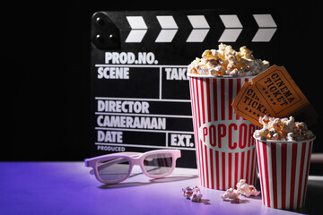 Delicious popcorn, tickets, glasses and clapper on table