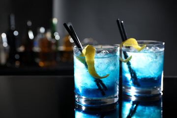 Glasses of fresh alcoholic cocktails on bar counter, space for text