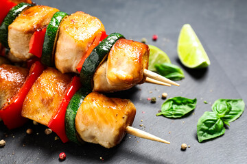 Delicious chicken shish kebabs with vegetables on black table, closeup