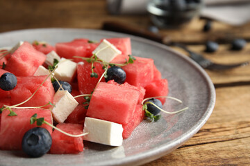 Delicious salad with watermelon, blueberries and feta cheese on wooden table, closeup