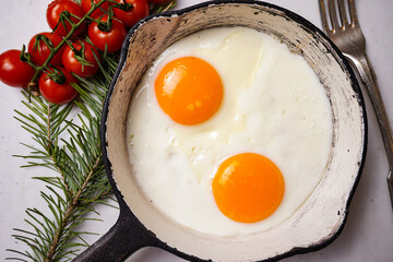 Homemade fried egg in a vintage pan and stylish cutlery on white background. View from above. 