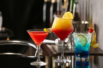 Different delicious cocktails on black table in bar