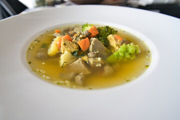 Ein weißer Teller Gemüsesuppe, Hühnersuppe mit Karotten, Leberknödel und Bio Gemüse, Produktbild
