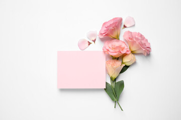 Beautiful Eustoma flowers and blank card on white background, flat lay. Space for text