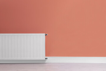 Modern radiator on color wall, space for text. Central heating system