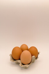 four fresh brown eggs in a egg carton against a light, white background