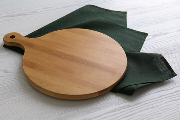 Empty wooden board and green napkin on white table