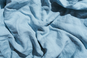 Flatlay of blue linen bed cloths and pillow, morning concept