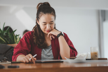smart Asian woman copywriter working freelance project in modern cafe. Businesswoman using...