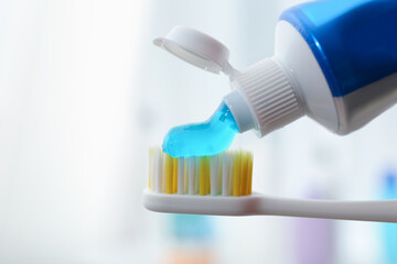 Applying toothpaste on brush against blurred background, closeup