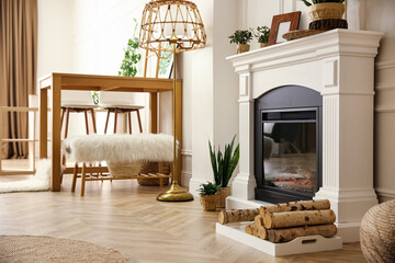 Elegant artificial fireplace and wooden table in room. Interior design