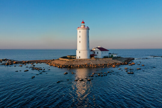 Panoramic aerial view of the Tolbukhin lighthouse. Artificial rocky island in the Gulf of Finland. The oldest Russian lighthouse. Baltic Sea. Stony coast. Summer day. Blue sky.
