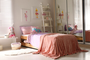 Fototapeta na wymiar Bed with beautiful linens in children's room. Modern interior design