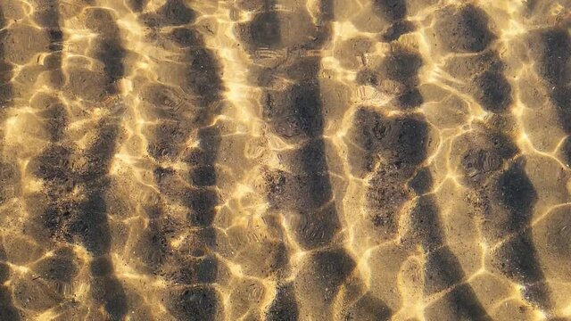 Golden beach water with light flares in slowmotion