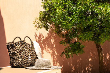 outdoor garden with deck chairs, wicker bag and hat, plant and ocher wall