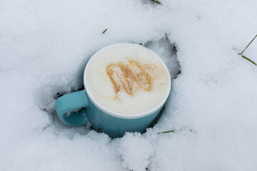 tasty cappuccino with caramel flavour in blue coffee cup in white snow
