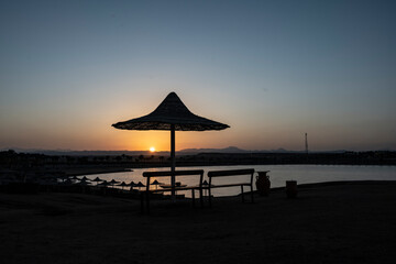 sunset on the background of a sandy beach with palm trees