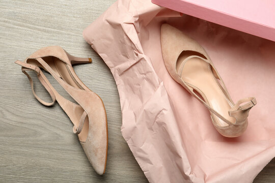 Pair of beautiful shoes and box on wooden background, flat lay