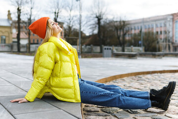 Stylish girl wearing yellow puffer and orange knitted hat