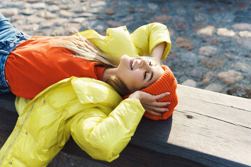 Stylish girl wearing yellow puffer and orange knitted hat