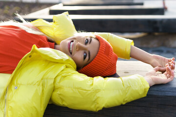 Stylish girl wearing yellow puffer and orange knitted hat