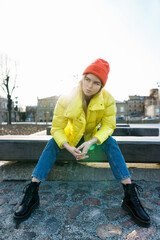 Stylish girl wearing yellow puffer and orange knitted hat
