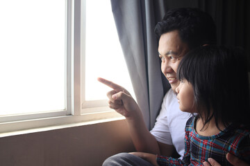Asian father and little baby daughter looking outside the window, family, hope and love