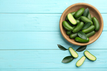 Fresh seedless avocados with green leaves on turquoise wooden table, flat lay. Space for text