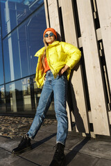 Stylish girl wearing yellow puffer and orange knitted hat