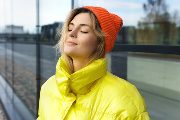 Stylish girl wearing yellow puffer and orange knitted hat