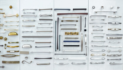 Fototapeta Big selection of handles cabinets parts on a white background shop window. samples of Metal and Stainless Steel handle styles on wooden kitchen cabinet with different Stainless Steel handles. obraz