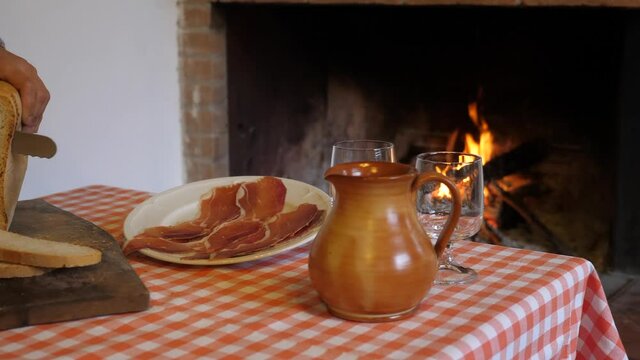 pane e prosciutto
Persona che taglia il pane e prepara dei gustosi panini davanti al fuoco del caminetto