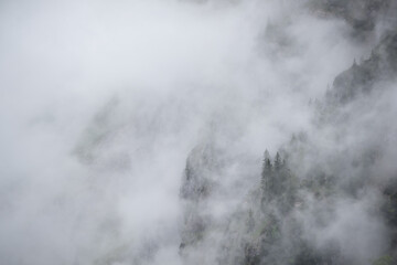 Fototapeta na wymiar Mist in the mountains of the Bavarian alps near Garmisch Partenkirchen with some barely visible trees no. 2