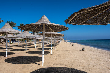 deserted beach with wicker umbrellas and lack of vacationers against the blue sky
