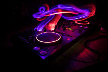 DJ console deejay-mixing desk in dark with colorful light. Mixer equipment entertainment DJ station.