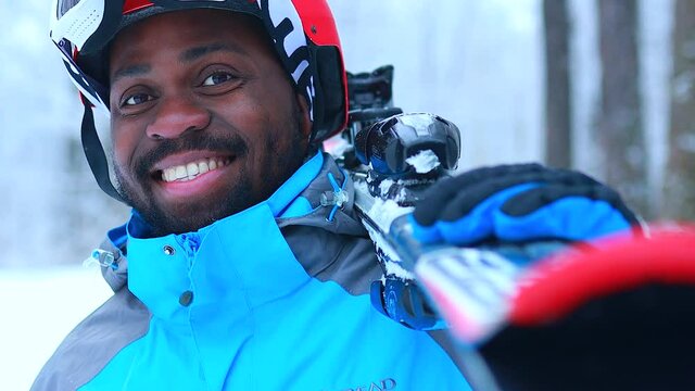 afro american man in blue jacket with ski outdoors in freeze forest